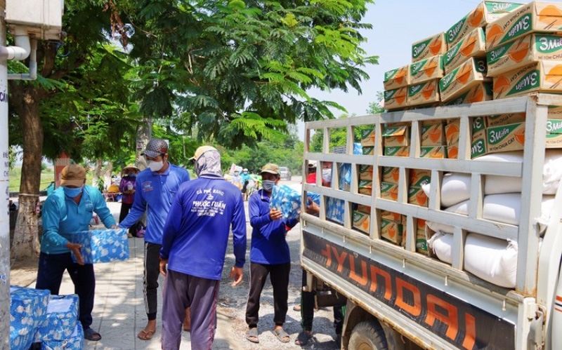 工人们正在将大米扛到旅居柬埔寨越南侨胞协会的车上。 图片：人民报