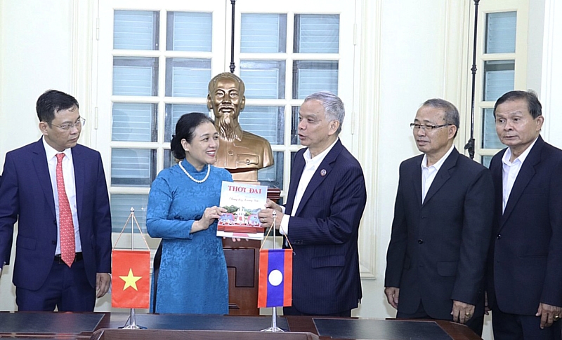 越南友好组织联合会主席阮芳娥向老挝和平与团结委员会主席宋玛·奔舍那赠送《时代杂志》作品。